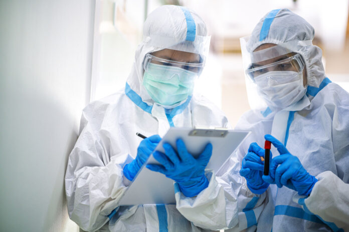 Asian doctor show corona or covid-19 blooding tube wearing ppe suit and face mask in hospital. Corona virus, Covid-19, virus outbreak, medical mask, hospital, quarantine or virus outbreak concept